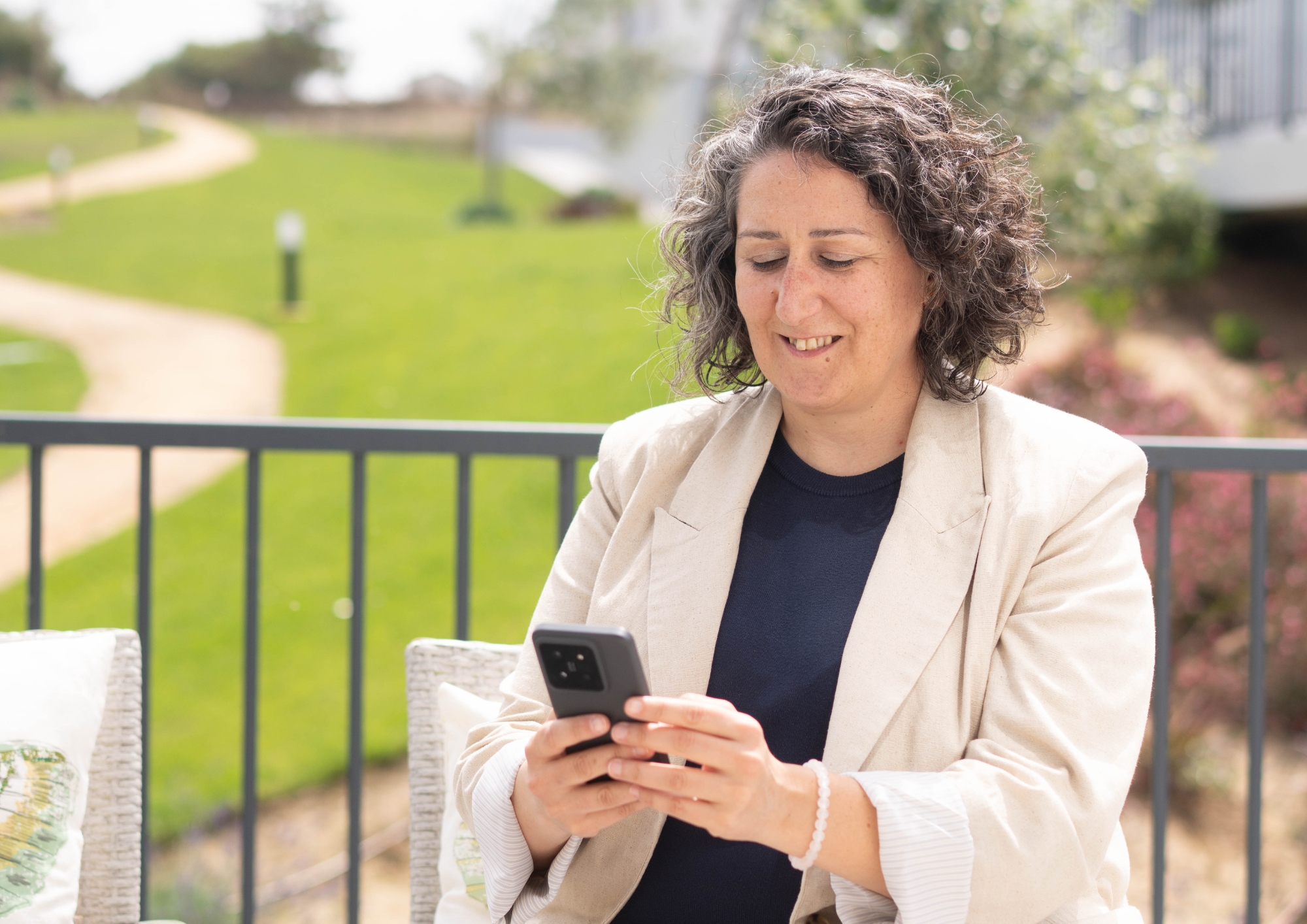 Ana Risso checking her phone on a terrace